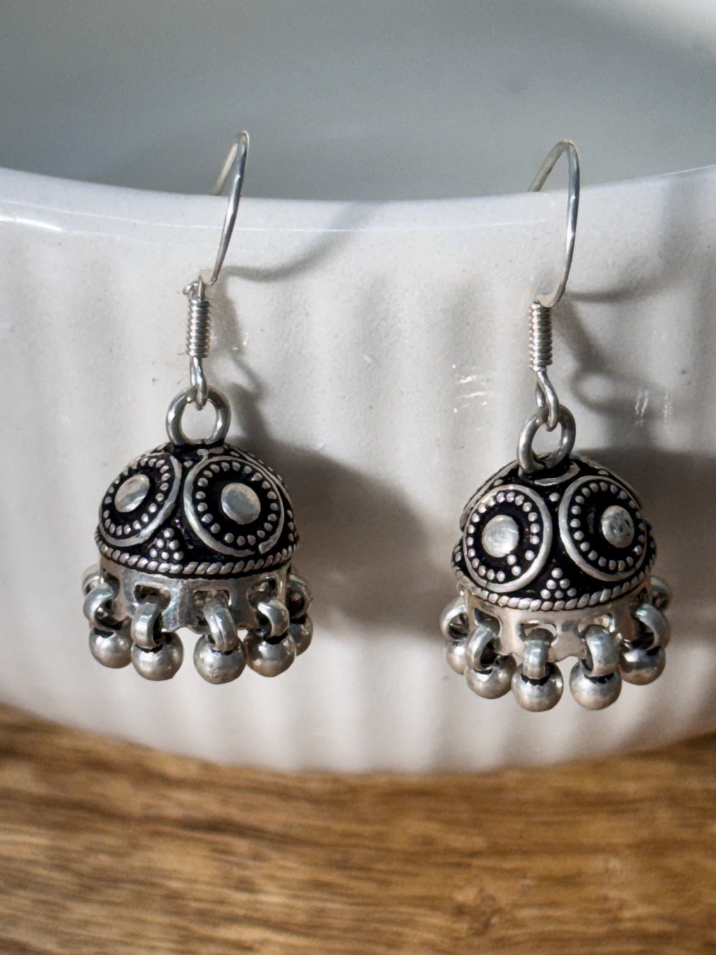 Pair of oxidised sterling silver dome jhumkis on french hooks with ghungroo bell fringes.