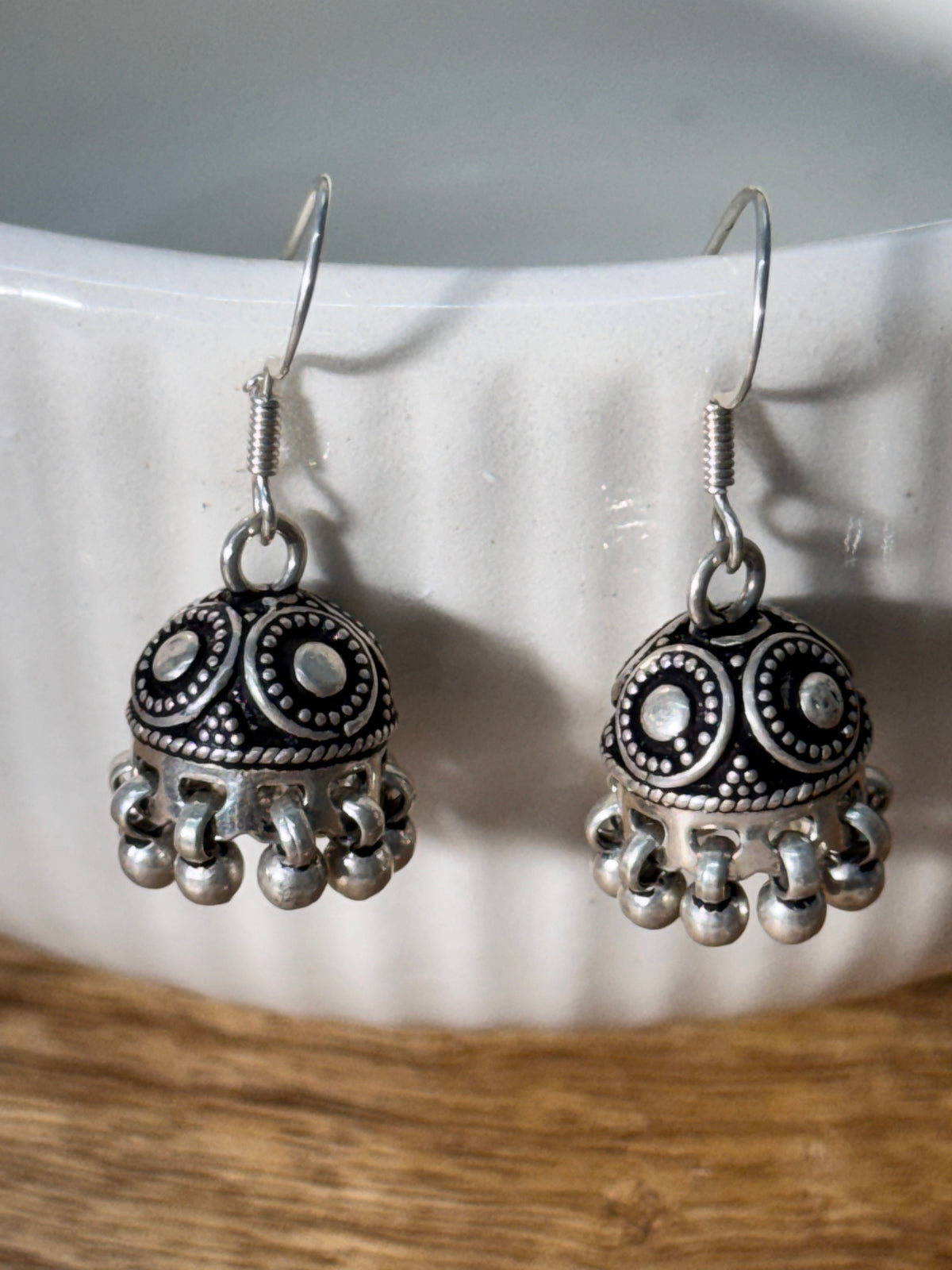Pair of oxidised sterling silver dome jhumkis on french hooks with ghungroo bell fringes.