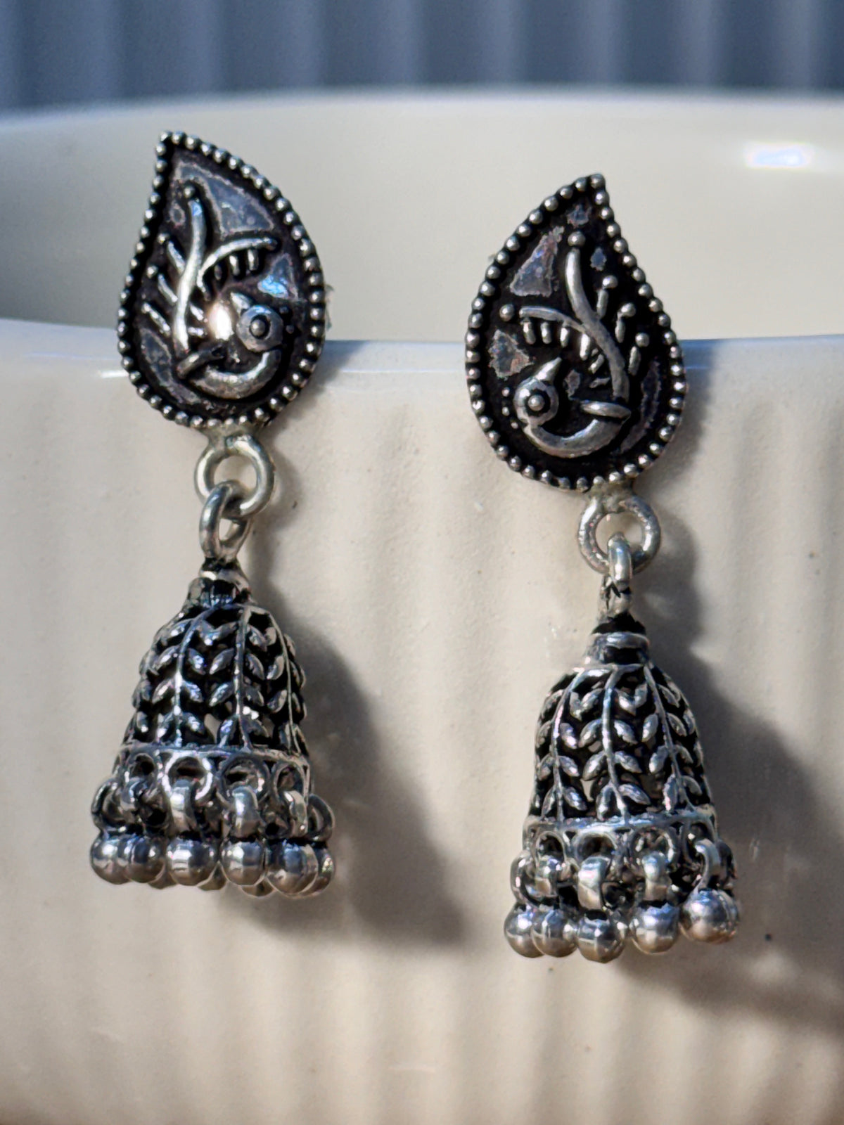 Pair of oxidised sterling silver paisley stud jhumkas with pierced cones and bead fringes.