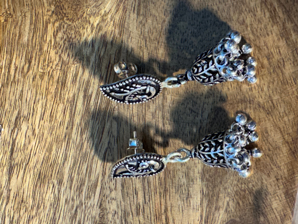 Close view of the paisley stud with its bird and leaf detail, above the fringed cone.