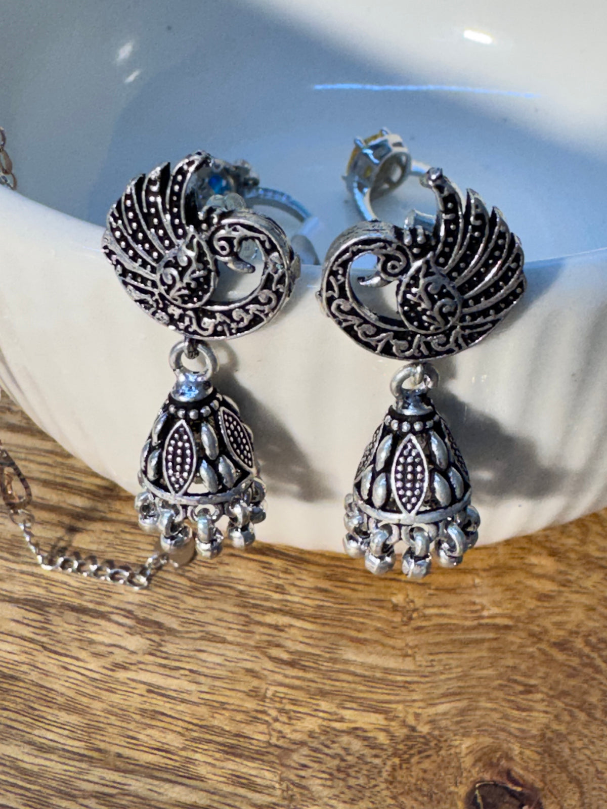 Close view of the crescent stud showing the two facing peacocks in oxidised relief.