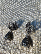 The peacock crescent jhumkas laid together, showing the beaded cones and fringes.