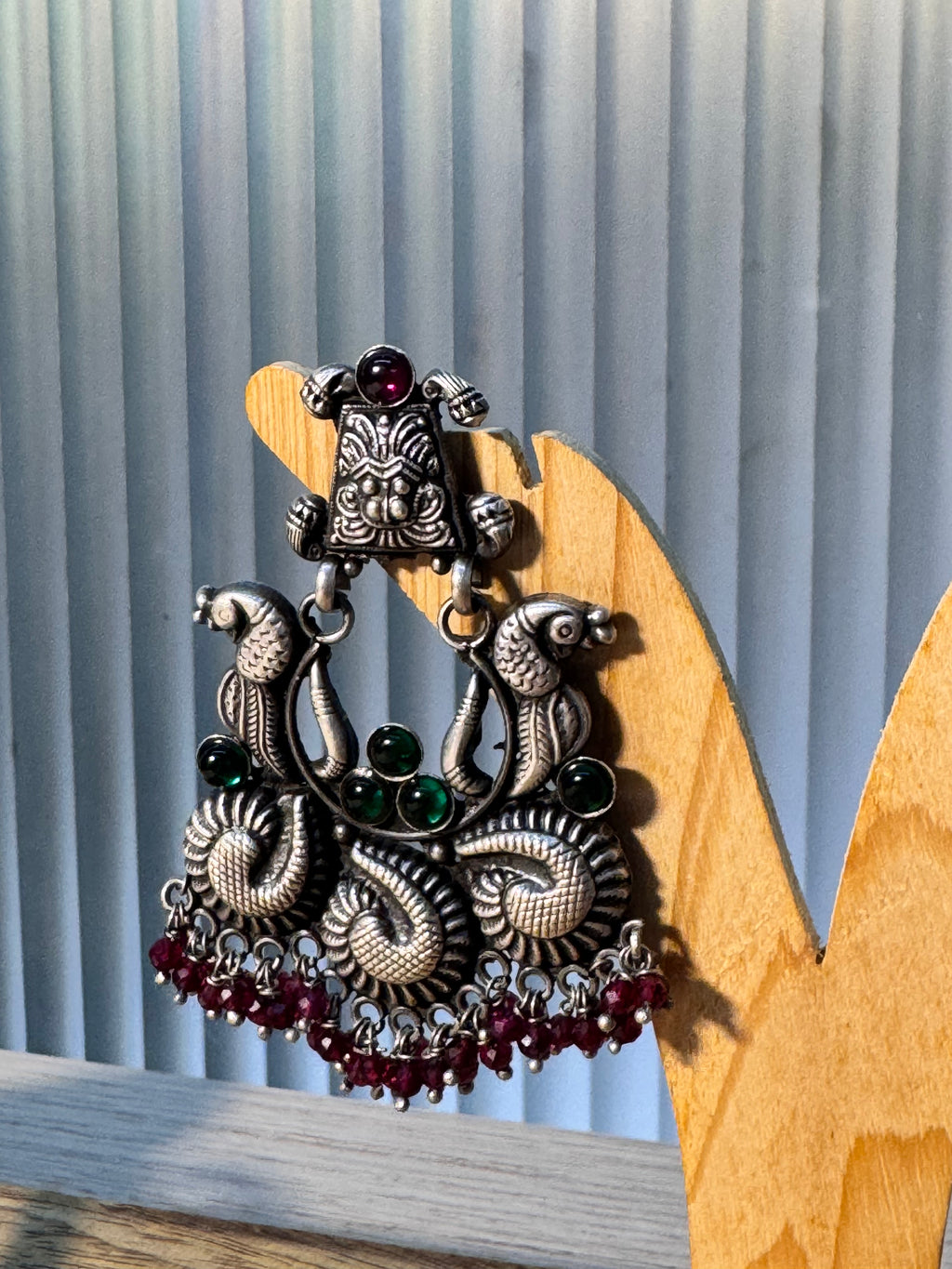 Detail of the facing peacocks and green glass stone accents on the temple style earring.