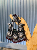 Detail of the facing peacocks and green glass stone accents on the temple style earring.