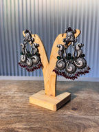 The statement earrings laid side by side, fringes of deep pink faceted glass beads fanned out.