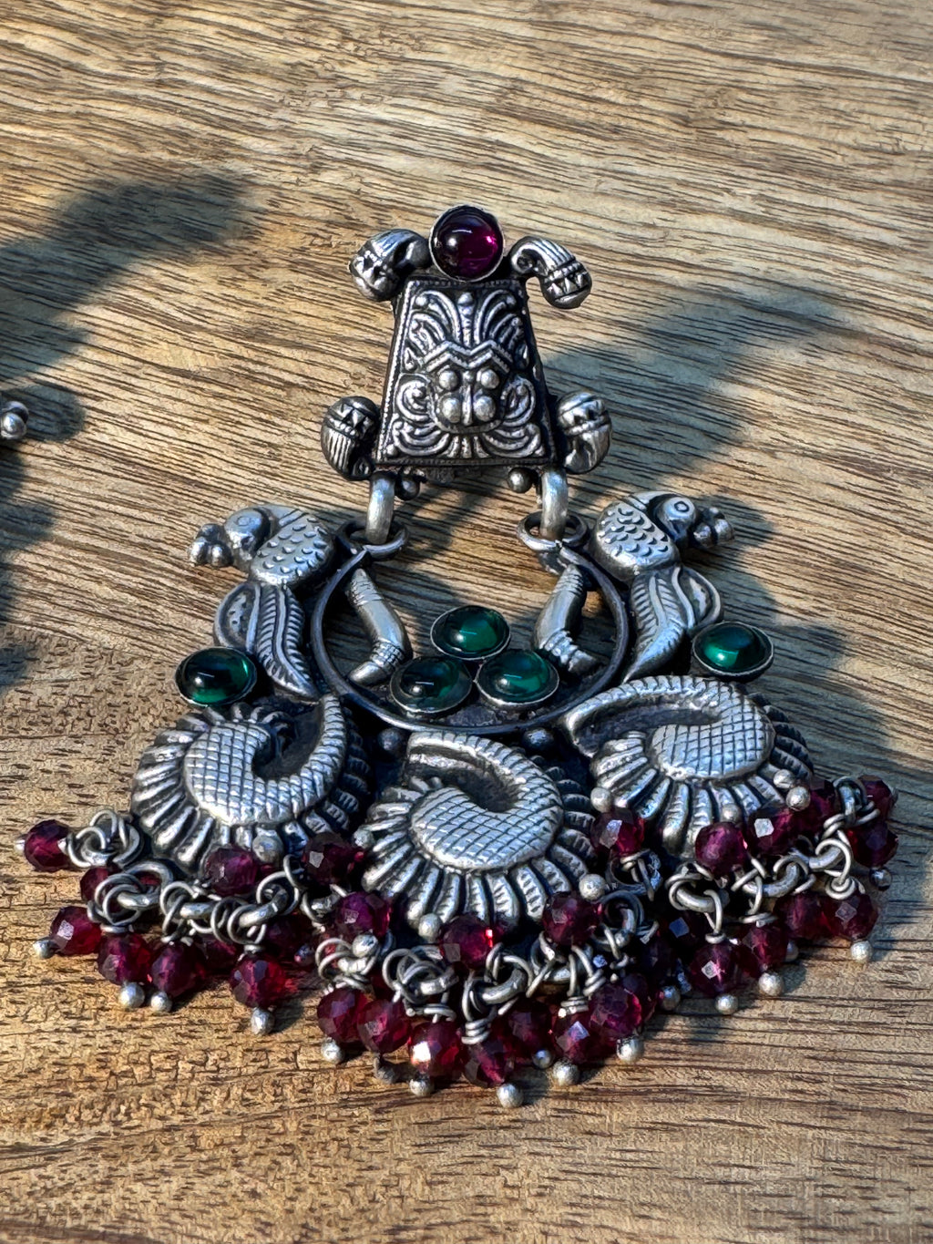 Full view of the temple style statement earrings with their pink bead fringes at rest.