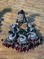 Full view of the temple style statement earrings with their pink bead fringes at rest.