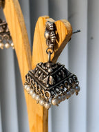 Both triangular dome pearl jhumkas resting together on a plain background.