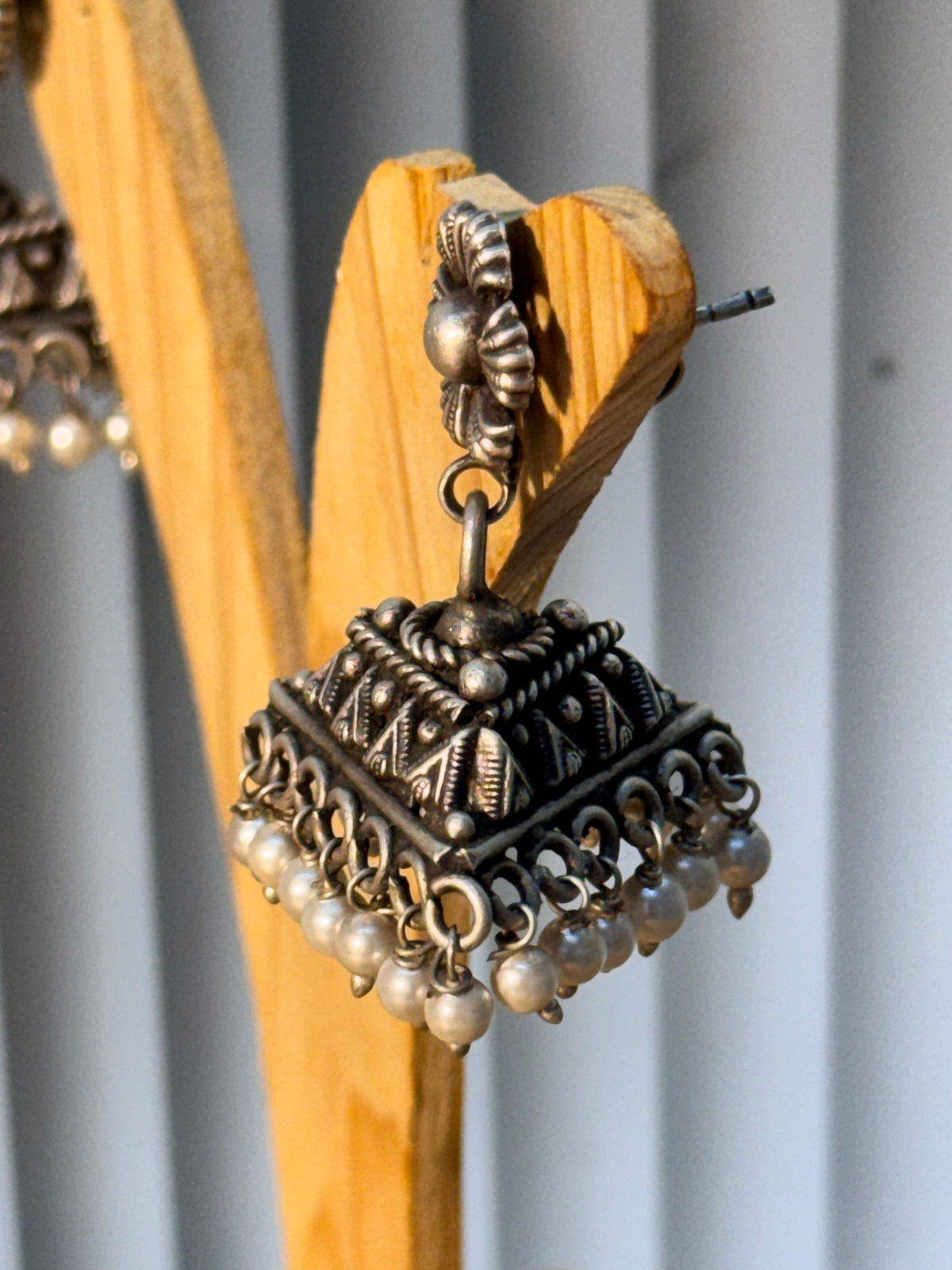 Both triangular dome pearl jhumkas resting together on a plain background.