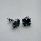 The green clover studs seen from a slight angle, showing the prongs on the clovers.
