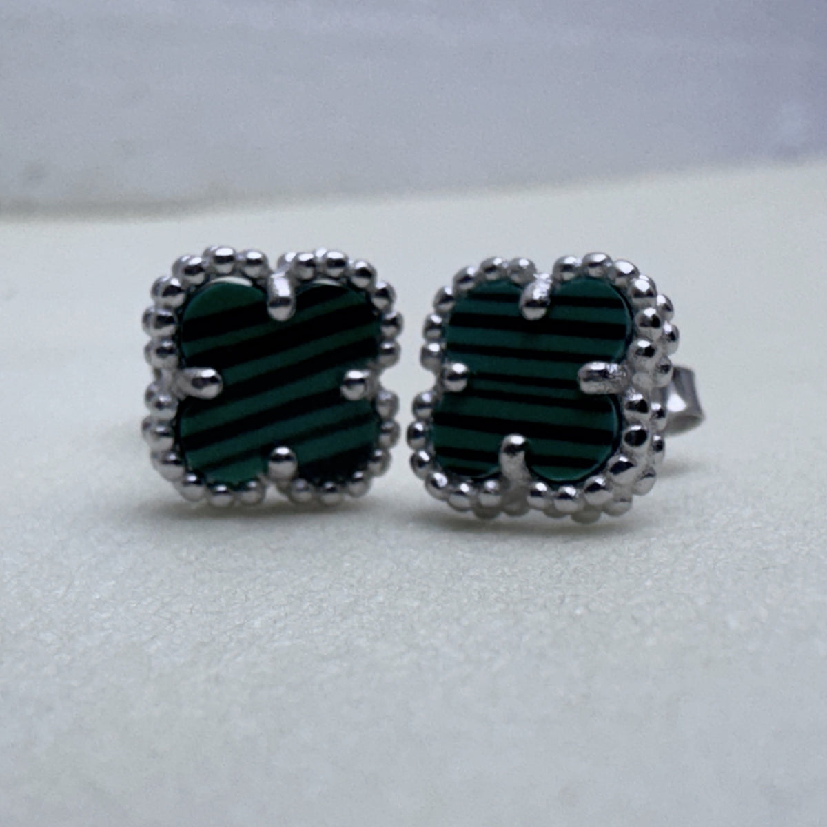 Close view of the green banded glass and the beaded edges of the two studs.