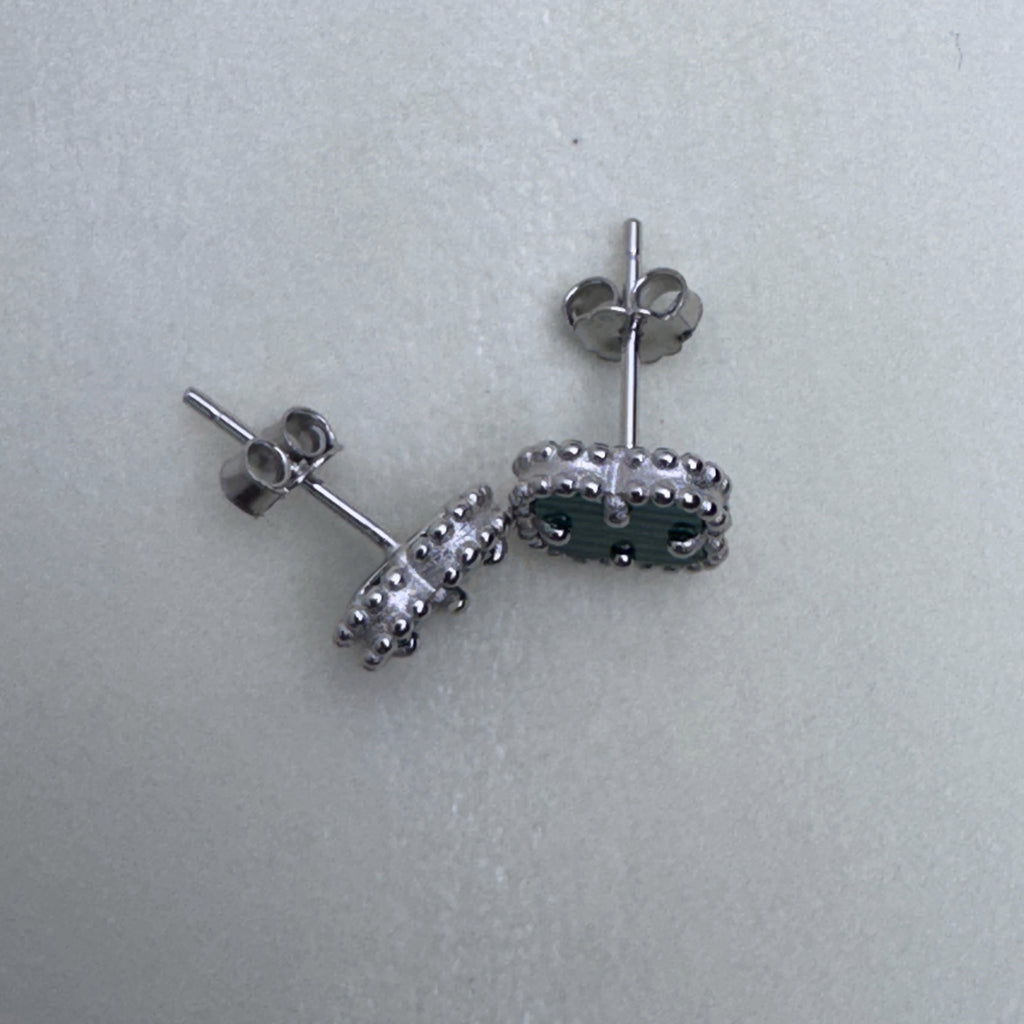 The clover studs seen from the side, showing the posts and push backs.