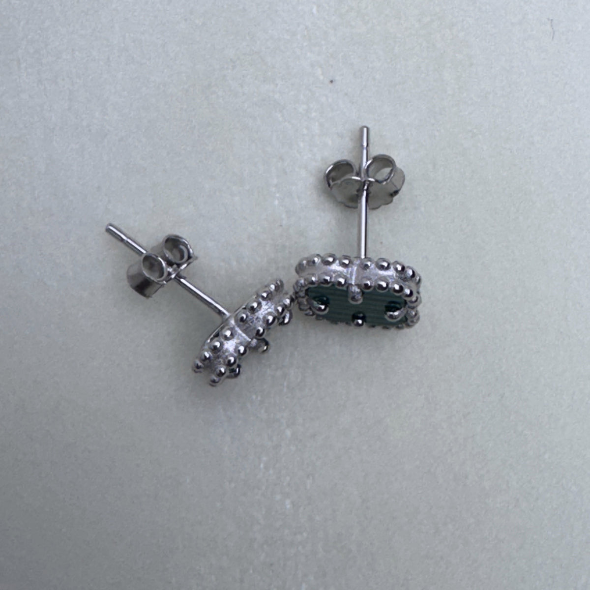 The clover studs seen from the side, showing the posts and push backs.