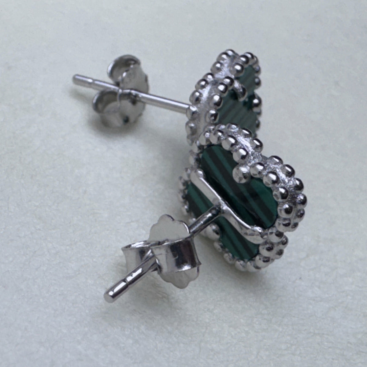 Close view of one green clover stud with its post and push back.