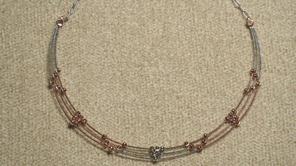 Detail of the necklace's textured sterling silver cable chain and lobster clasp against beige woven fabric.
