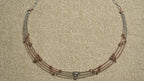 Detail of the necklace's textured sterling silver cable chain and lobster clasp against beige woven fabric.