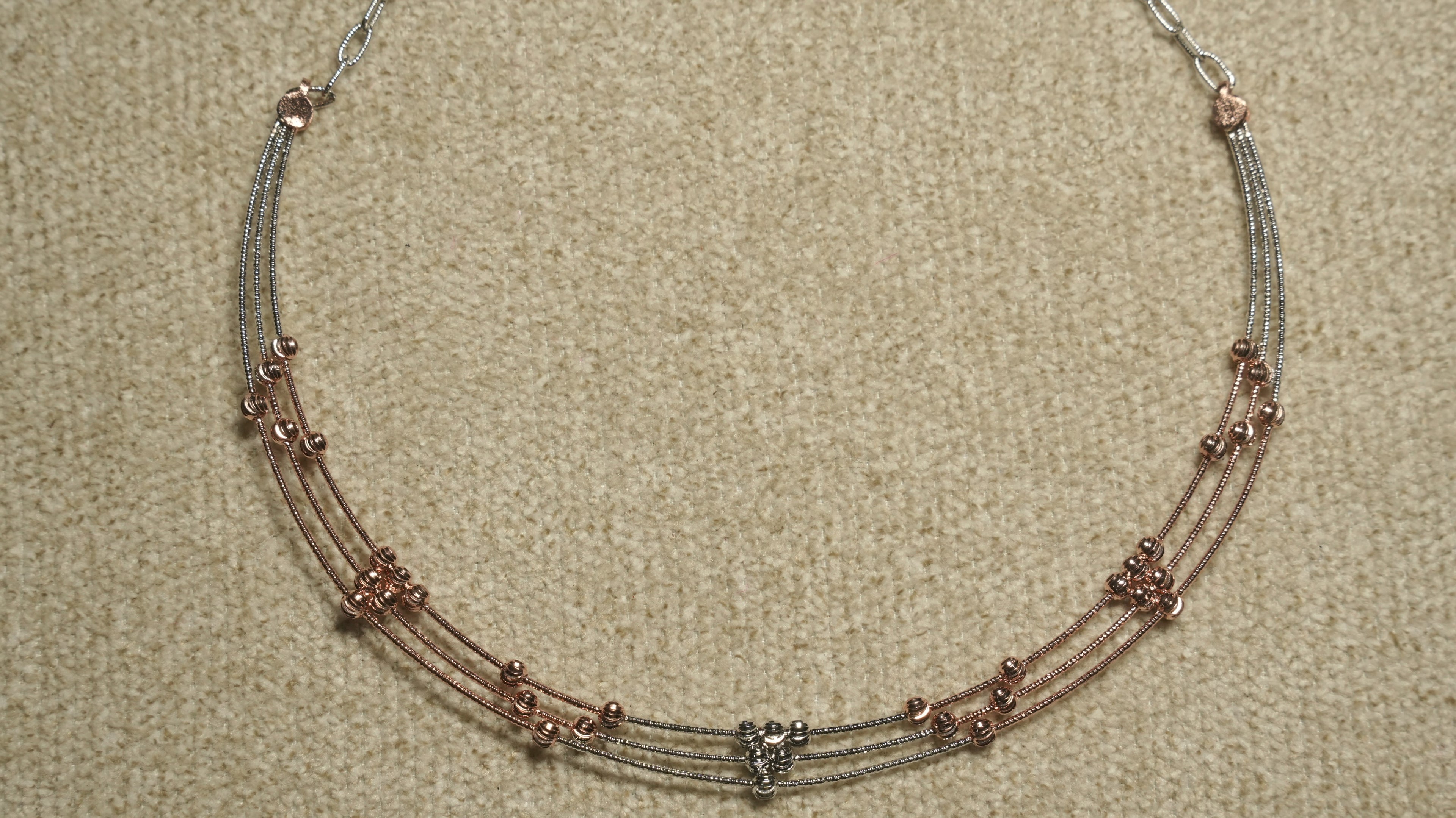 Detail of the necklace's textured sterling silver cable chain and lobster clasp against beige woven fabric.