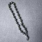 Sterling silver bead mala for a small idol with an engraved leaf drop, large size, on a grey surface.