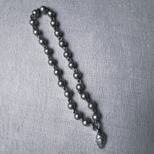 Sterling silver bead mala for a small idol with an engraved leaf drop, large size, on a grey surface.