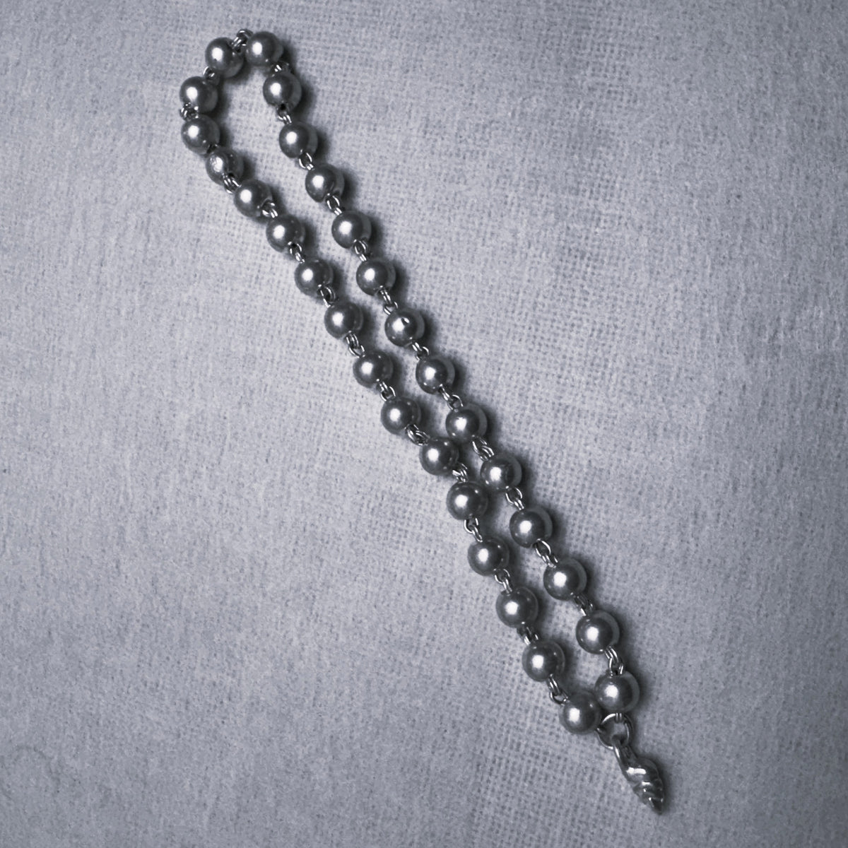 The large silver bead mala folded double to show the linked beads along its length.