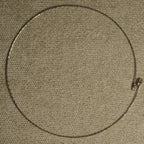 Full circle view of the slim sterling silver wire collar laid flat on beige fabric, showing the small lobster clasp.
