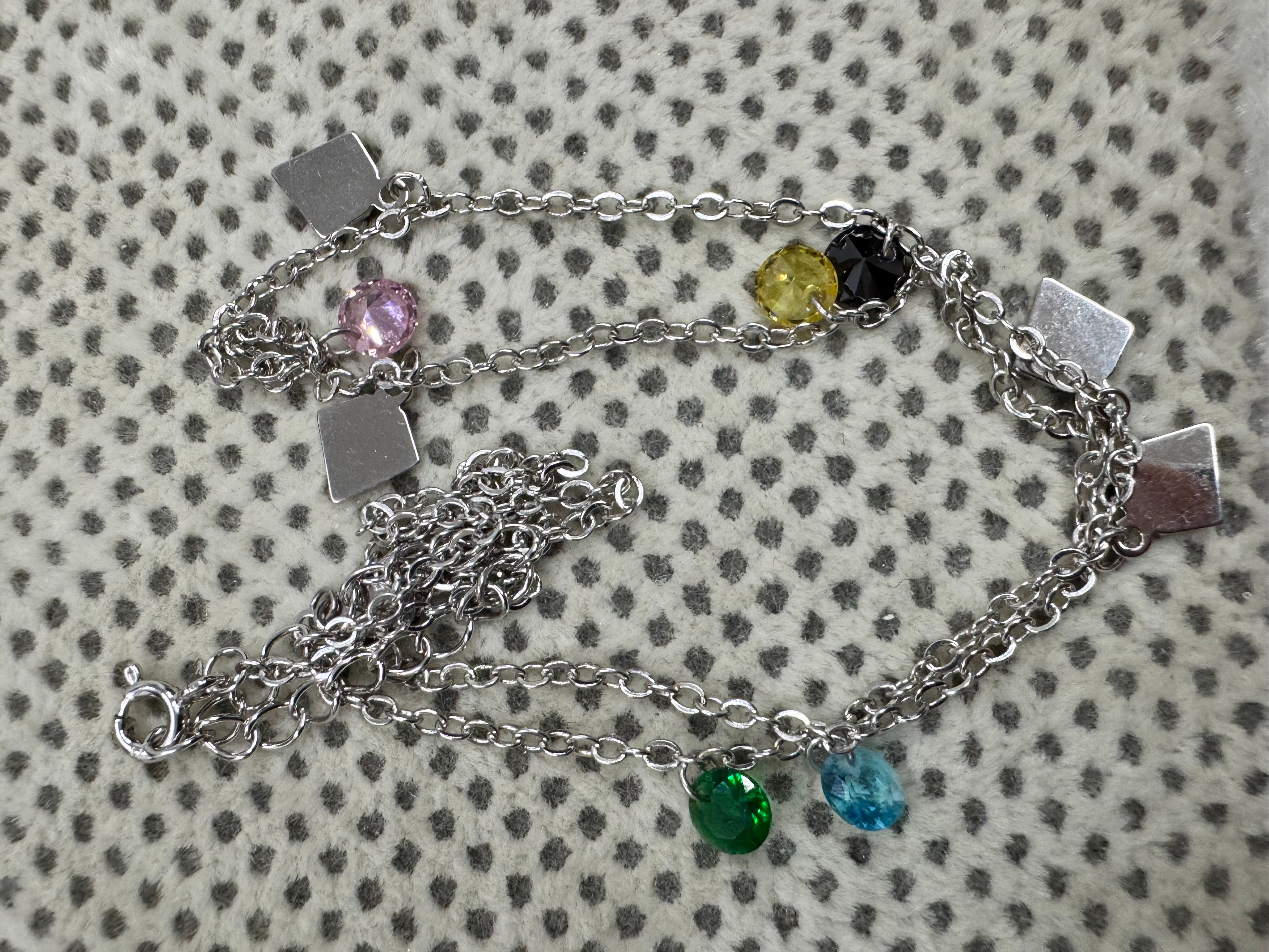 The full sterling silver cable chain necklace coiled on spotted cream fabric, with its spring ring clasp at the lower left.