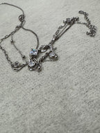The full three-strand sterling silver necklace loosely coiled on grey fabric, showing the clasp, extender chain and all stone stations.