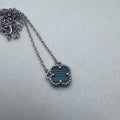 Sterling silver necklace with a green glass clover in a beaded frame, on a cable chain.