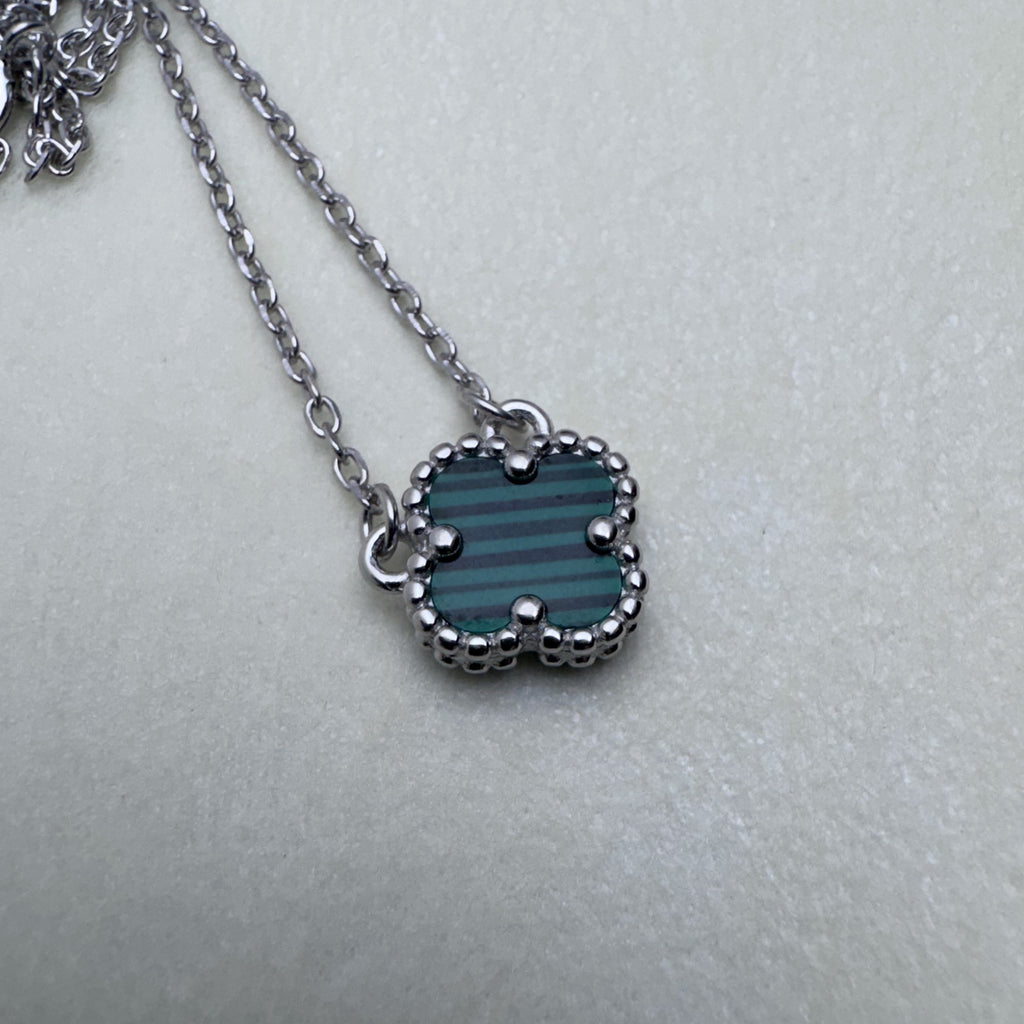 The green clover pendant on the silver cable chain, seen from above.