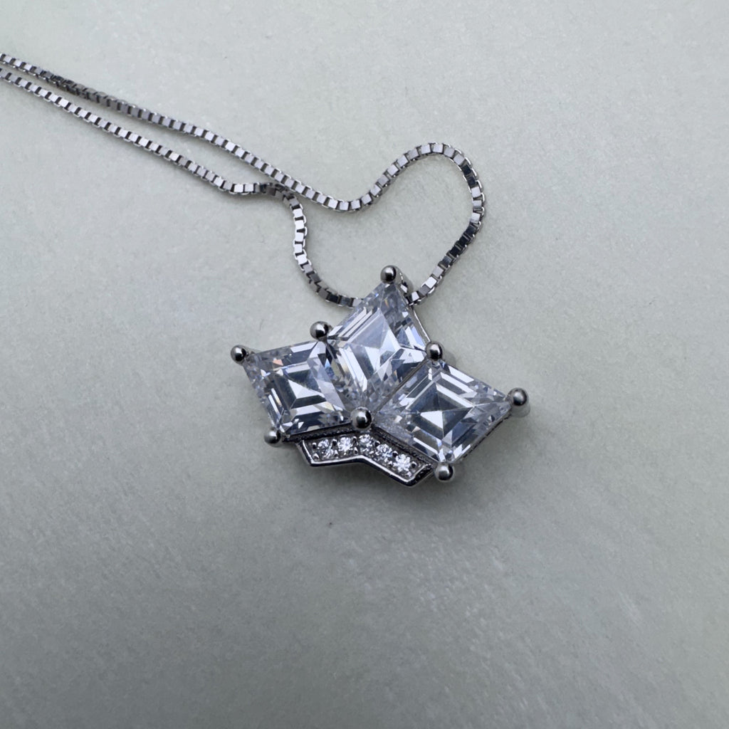 The crown pendant on its box chain, seen from above.