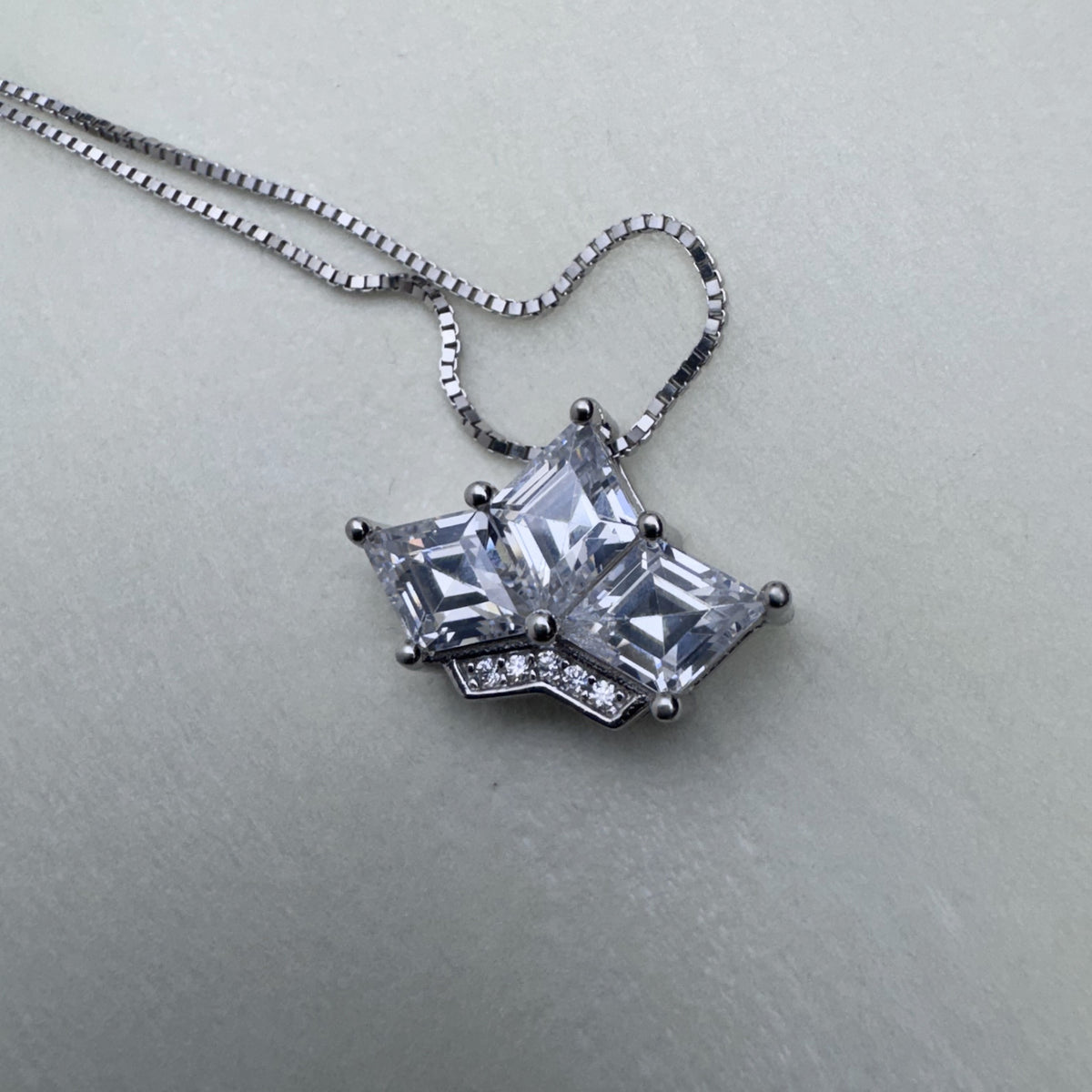 The crown pendant on its box chain, seen from above.