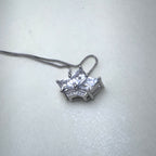 The crown pendant necklace laid on a pale surface with the chain looped above it.