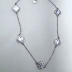Sterling silver station necklace with five grey mother of pearl clovers laid out on a pale surface.