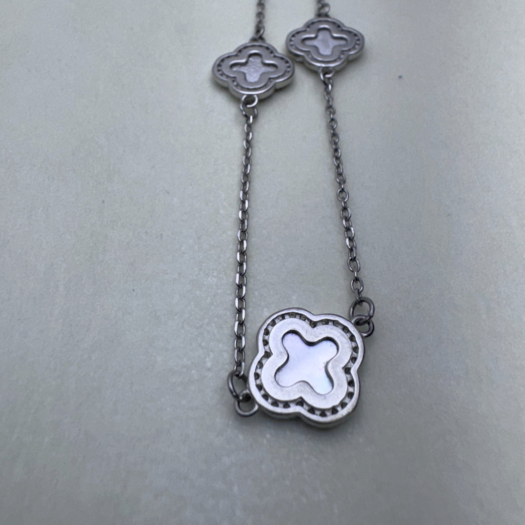 Close view of two mother of pearl clovers in beaded silver frames on the cable chain.