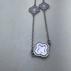 Close view of two mother of pearl clovers in beaded silver frames on the cable chain.