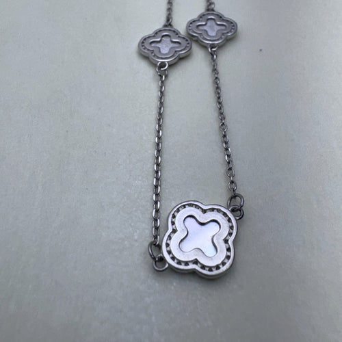 Close view of two mother of pearl clovers in beaded silver frames on the cable chain.