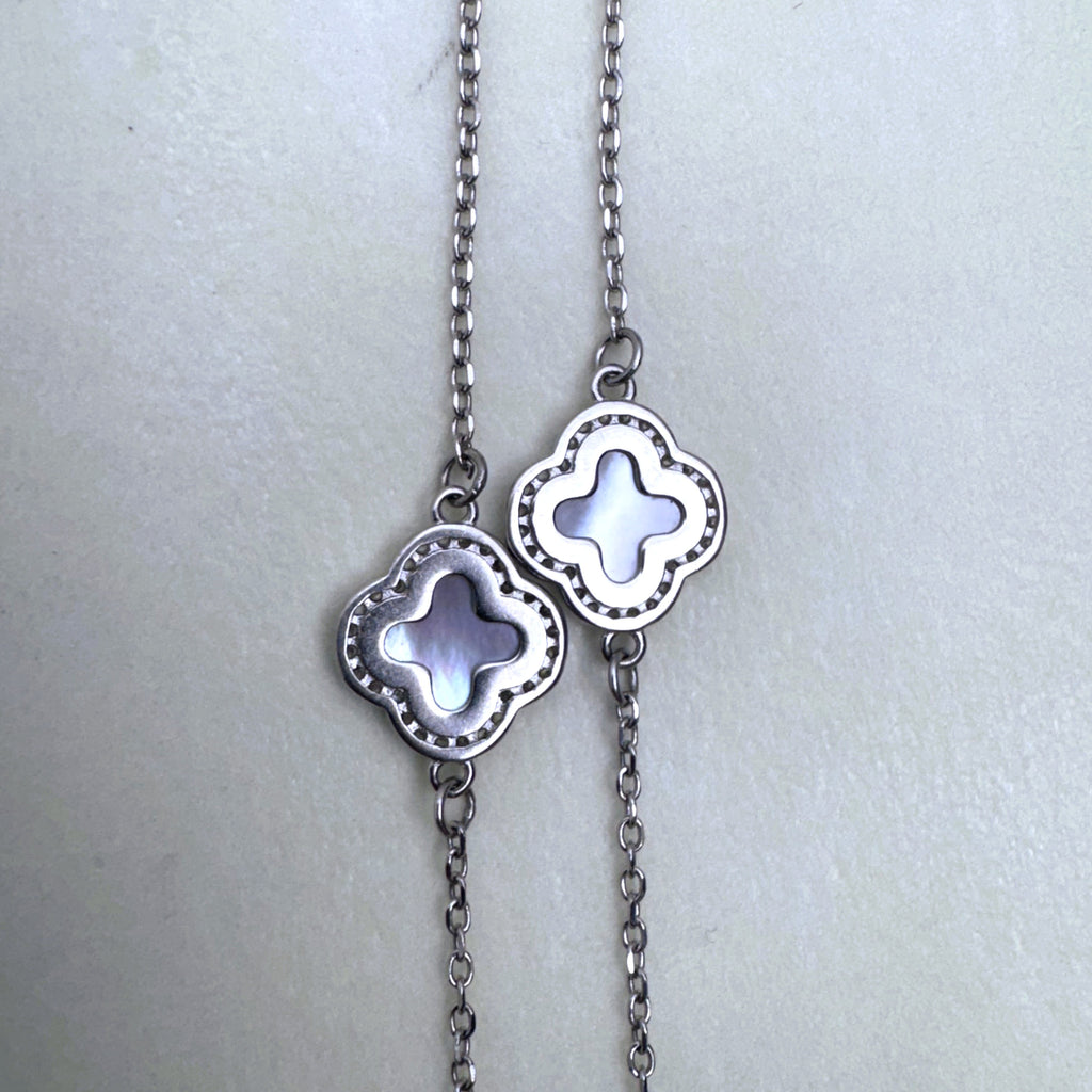 Two clovers of the station necklace side by side, showing the grey shell and the beaded edge.