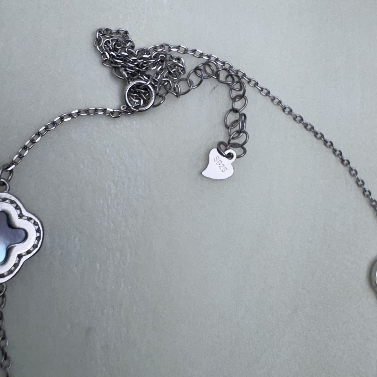 The lobster clasp, extender chain and tag of the silver station necklace.
