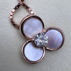 Close view of the pale mother of pearl petals in rose-tone bezels around the centre stone.