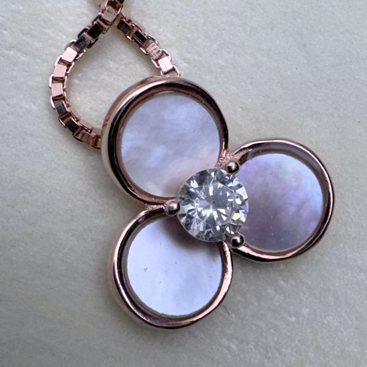 Close view of the pale mother of pearl petals in rose-tone bezels around the centre stone.
