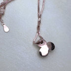 The back of the three-petal pendant on the rose-tone chain.