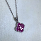 Sterling silver clover pendant necklace filled with red glass stones, hanging from a cable chain.