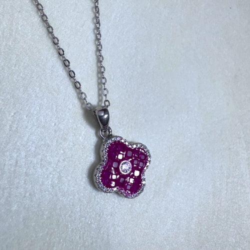 Sterling silver clover pendant necklace filled with red glass stones, hanging from a cable chain.