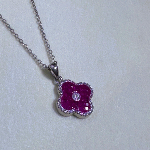 The red clover pendant on its silver cable chain, seen slightly from the side.