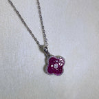 Close view of the square red glass stones and the pave border of the clover pendant.