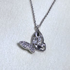 The silver butterfly pendant hanging from the cable chain on a pale surface.