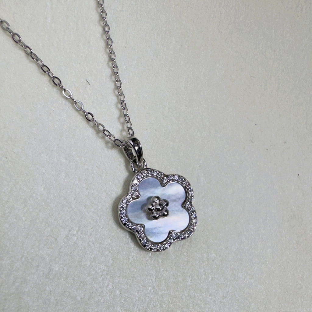 Sterling silver flower pendant necklace with a white mother of pearl face and pave border, on a cable chain.