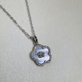 Sterling silver flower pendant necklace with a white mother of pearl face and pave border, on a cable chain.