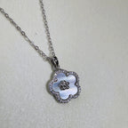 Sterling silver flower pendant necklace with a white mother of pearl face and pave border, on a cable chain.