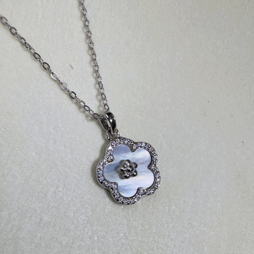 Sterling silver flower pendant necklace with a white mother of pearl face and pave border, on a cable chain.